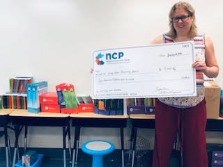 Dr. Jennifer McKee of Jersey Shore Elementary School holds a giant check for $5000 | NCP Cares donation to schools